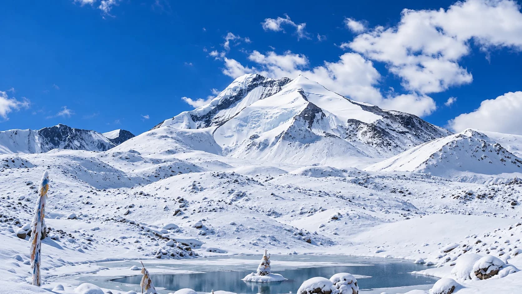 Snow-covered mountain above an icy pool beneath a blue sky